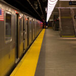Empty subway station platform with a train and exit signs