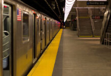 Empty subway station platform with a train and exit signs