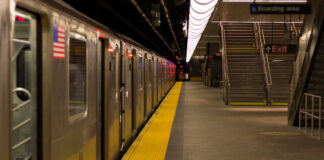 Empty subway station platform with a train and exit signs
