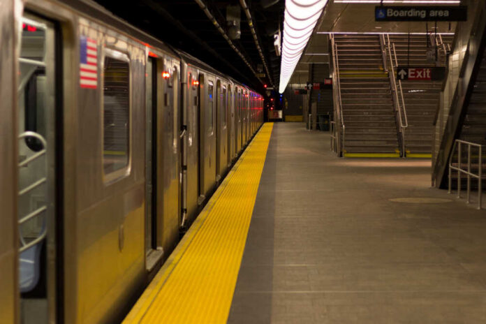 Empty subway station platform with a train and exit signs