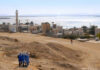 A group of women in blue walking in a desert landscape with historical buildings in the background