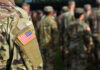 Close-up of a soldier's uniform with an American flag patch in a gathering of military personnel