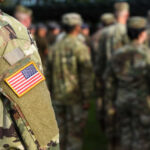 Close-up of a soldier's uniform with an American flag patch in a gathering of military personnel