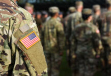 Close-up of a soldier's uniform with an American flag patch in a gathering of military personnel