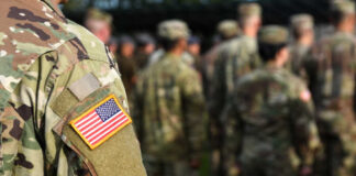 Close-up of a soldier's uniform with an American flag patch in a gathering of military personnel