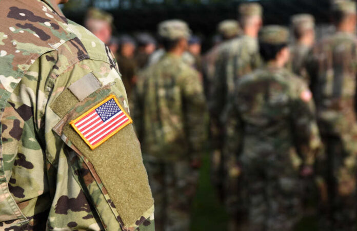 Close-up of a soldier's uniform with an American flag patch in a gathering of military personnel