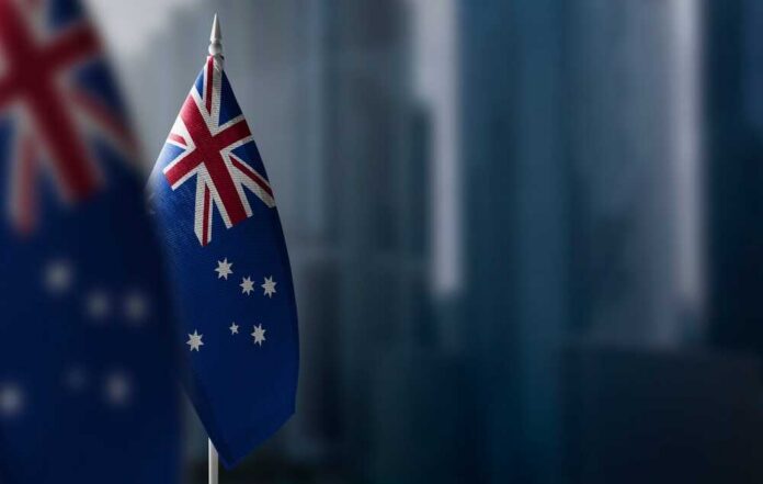 Small,Flags,Of,Australia,On,A,Blurry,Background,Of,The Australian flag displayed on a flagpole with a blurred city background