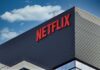Close-up of the Netflix logo on a modern building against a blue sky