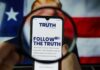 A smartphone displaying the TRUTH Social app, viewed through a magnifying glass