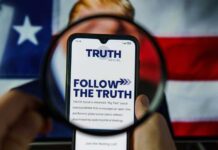 A smartphone displaying the TRUTH Social app, viewed through a magnifying glass