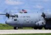 C-130 military aircraft with crew waving an American flag
