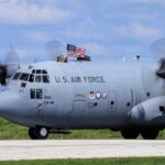 C-130 military aircraft with crew waving an American flag