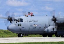 C-130 military aircraft with crew waving an American flag
