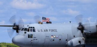 C-130 military aircraft with crew waving an American flag