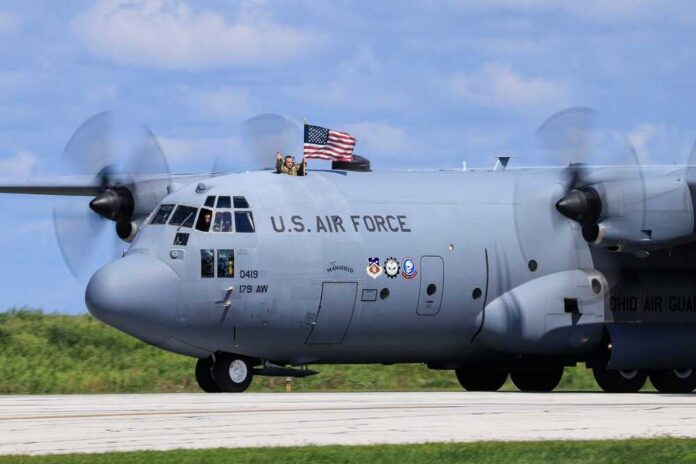 C-130 military aircraft with crew waving an American flag