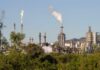 Industrial refinery with smoke stacks and flames against a clear sky