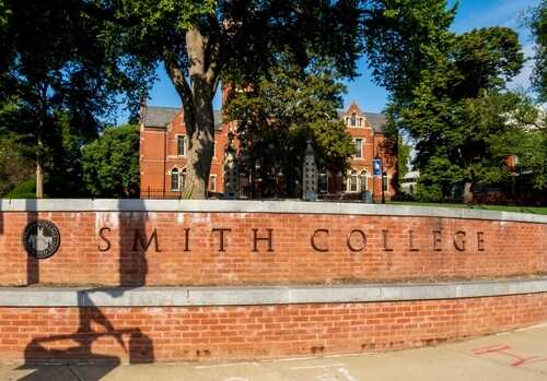 Sign for Smith College in front of a brick building surrounded by trees