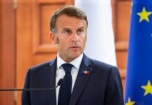 Norway’s Unexpected Defense Shift: France Takes Lead A political leader speaking at a press conference with flags in the background
