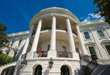 Exterior view of the White House with columns and blue sky