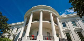 Exterior view of the White House with columns and blue sky
