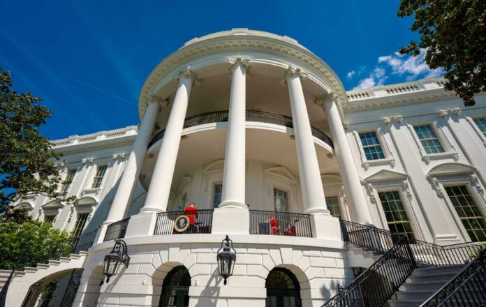 Exterior view of the White House with columns and blue sky
