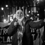 A woman speaking into a microphone at a nighttime protest