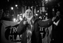 A woman speaking into a microphone at a nighttime protest