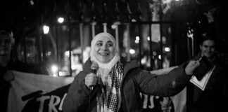 A woman speaking into a microphone at a nighttime protest