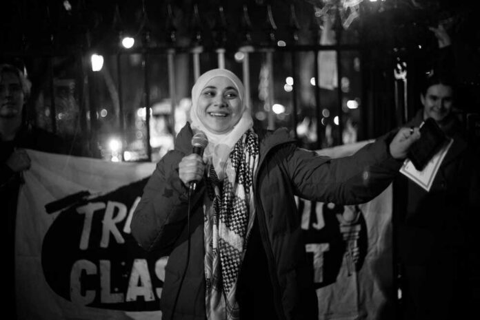 A woman speaking into a microphone at a nighttime protest