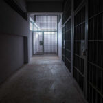 A dimly lit prison corridor with jail cells on either side