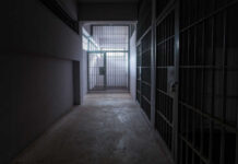 A dimly lit prison corridor with jail cells on either side