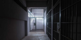 A dimly lit prison corridor with jail cells on either side