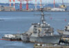 naval destroyer moored at a busy harbor