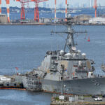 naval destroyer moored at a busy harbor