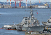naval destroyer moored at a busy harbor