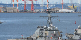 naval destroyer moored at a busy harbor