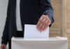 Hand placing a ballot into a box