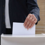 Hand placing a ballot into a box