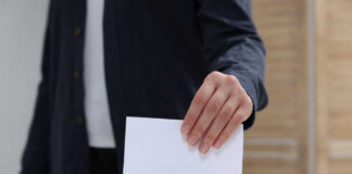 Hand placing a ballot into a box
