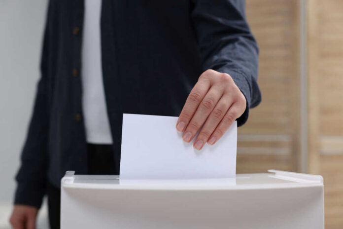 Hand placing a ballot into a box
