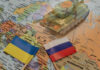 Toy tank with Ukraine and Russia flags on map.