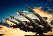 Nuke Ramp-Up Exposed — Washington Distracted? Cruise missile launcher with missiles pointed upwards against a sunset sky