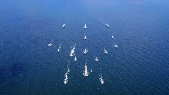Aerial view of multiple naval ships operating in the ocean