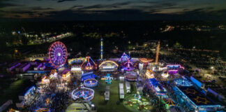Nighttime aerial view of a brightly lit carnival with rides and crowds