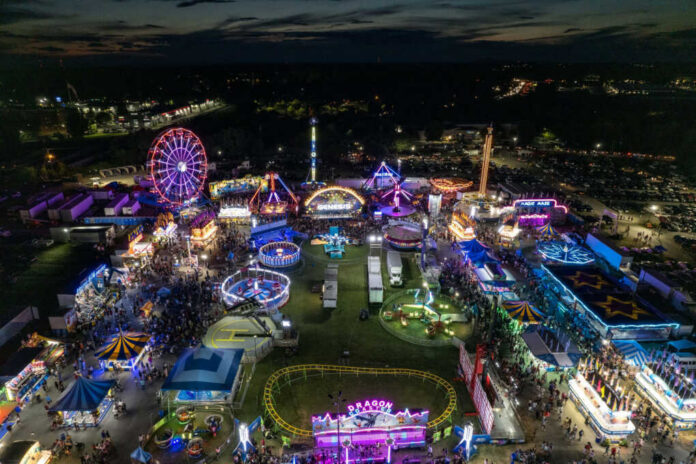 Nighttime aerial view of a brightly lit carnival with rides and crowds