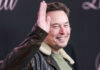 Man in leather jacket smiling and waving