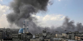 Cityscape with smoke rising, buildings, and a mosque.