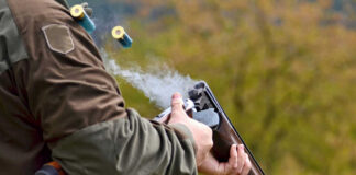 Person reloading shotgun outdoors with cartridges ejecting
