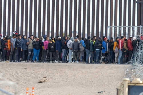 immigrant2497167391 Large group of people standing near border fence