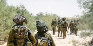 Soldiers walking in formation along a sandy path